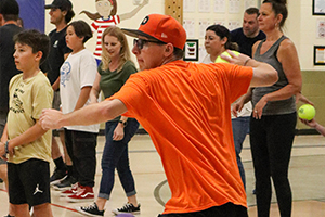 Adult in orange t-shirt tossing ball