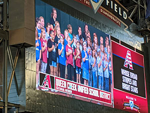 Jumbotron image of Queen Creek choir students singing the national anthem at a Diamondbacks baseball game.